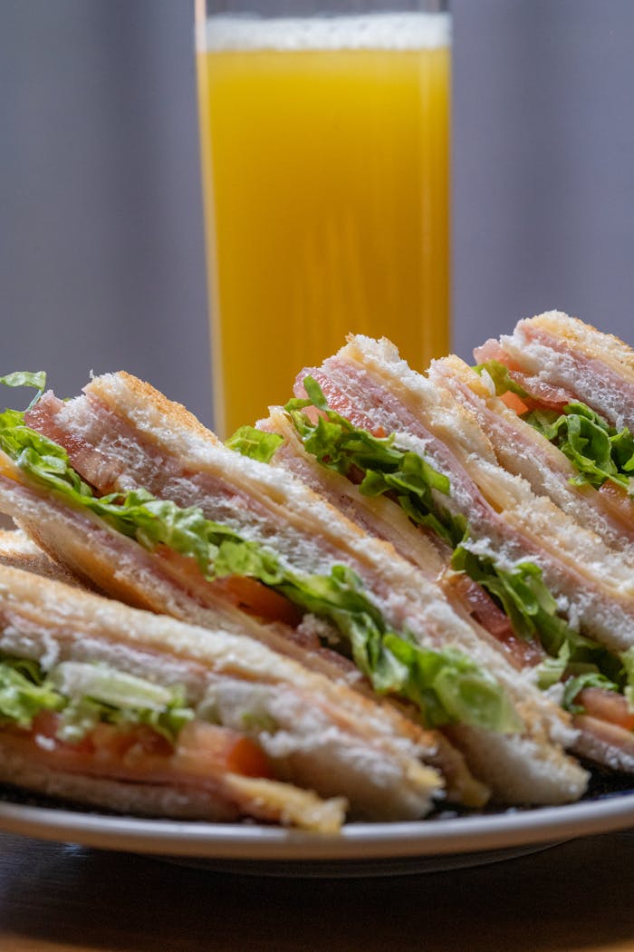 Savor a hearty club sandwich with fresh lettuce and ham, perfect with orange juice.